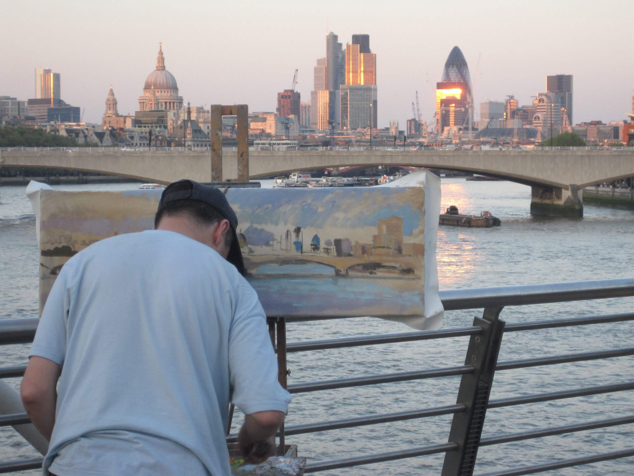 artist on a London bridge painting the London skyline