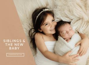 a todler holding her baby sibling